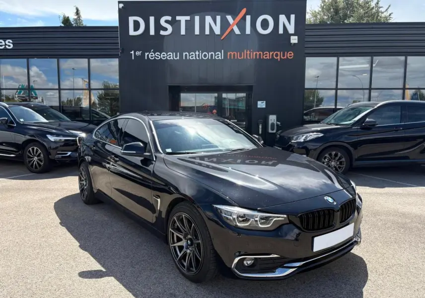 BMW Série 4 Gran Coupé noir saphir vue 3/4 avant droit avec jantes alliage et calandre chromée devant concessionnaire Distinxion