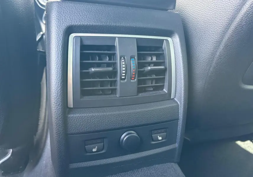 Détail des aérateurs arrière noirs avec commandes de chauffage des sièges dans une BMW Série 4 Gran Coupe noire.