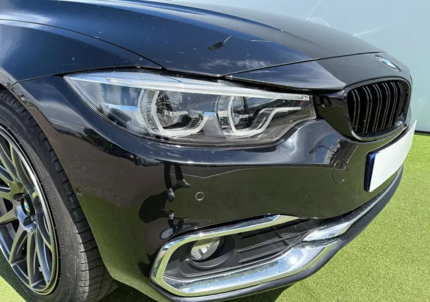 Gros plan sur l'avant droit noir saphir d'une BMW Série 4 Gran Coupe avec phares Full LED et jante alliage 18 pouces.