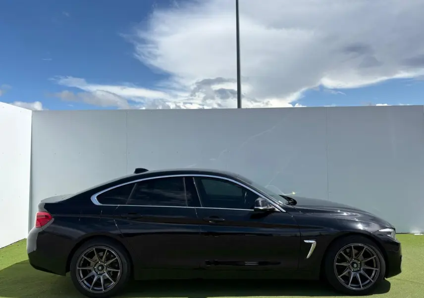 Profil côté gauche d'une BMW Série 4 Gran Coupé 420d noir saphir avec jantes alliage 18 pouces et vitres teintées.
