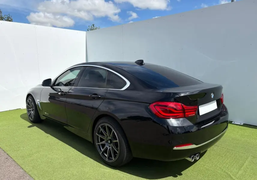 BMW Série 4 Gran Coupé noir saphir vue 3/4 arrière droit avec jantes alliage et double sortie d’échappement chrome