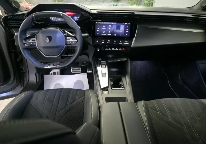 Intérieur avant du Peugeot 408 2024 avec tableau de bord numérique, volant cuir perforé et console centrale moderne.