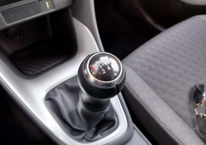 Gros plan sur le levier de vitesses manuel noir dans l’habitacle gris d’une Toyota Yaris blanche 2023.