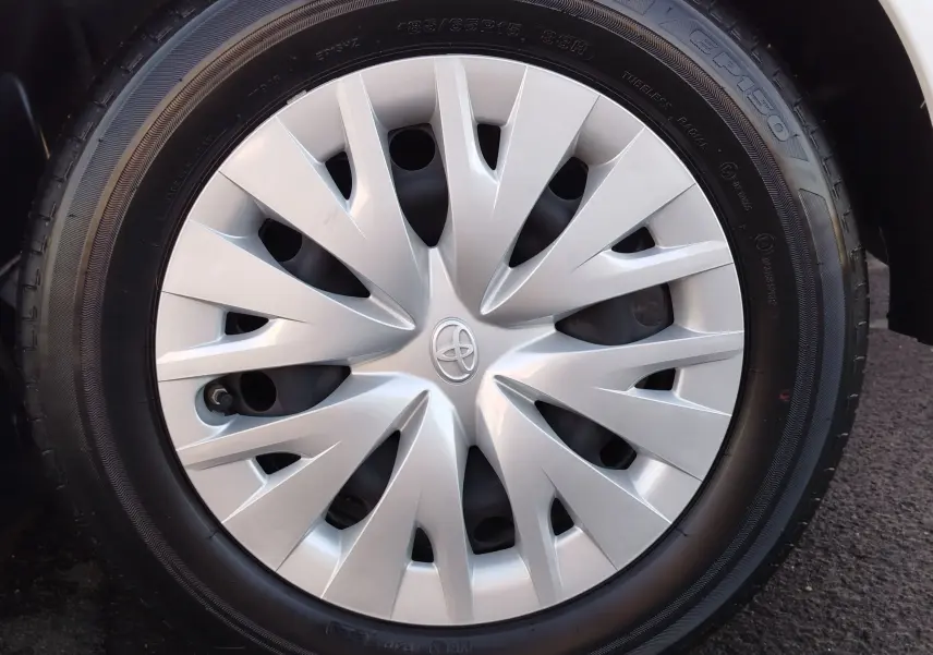 Gros plan sur la roue avant droite d'une Toyota Yaris blanche avec enjoliveur argenté au design moderne.