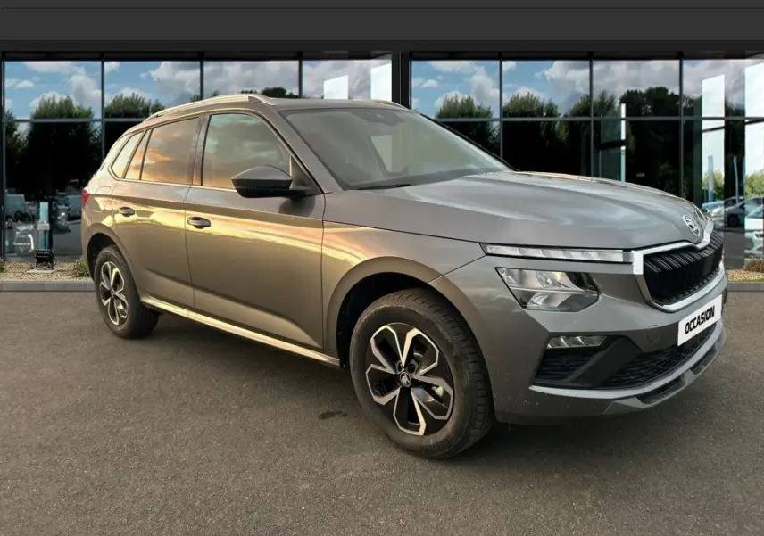 Skoda Kamiq gris clair vu en 3/4 avant droit, avec calandre noire et jantes alliage bicolores.