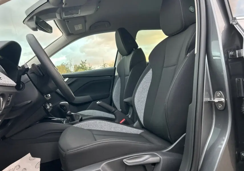 Intérieur de la Skoda Kamiq gris clair, vue côté conducteur montrant sièges tissu noir et gris avec surpiqûres blanches.