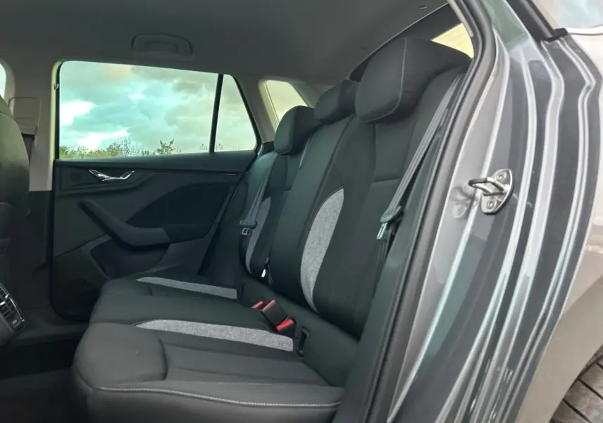 Vue intérieure côté droit sur la banquette arrière noire et grise du Skoda Kamiq gris clair 2025 avec porte ouverte.