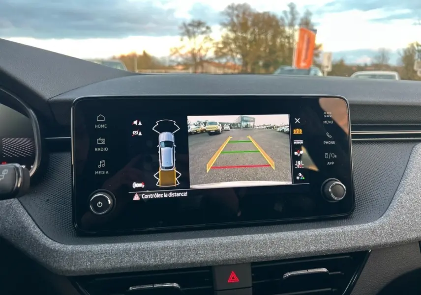 Écran tactile central du tableau de bord du Skoda Kamiq gris clair, affichant la caméra de recul et les capteurs de stationnement.