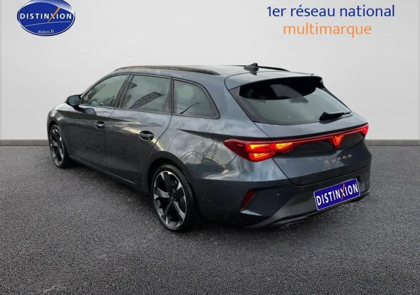 Vue 3/4 arrière droite d'une CUPRA LEON ST gris magnétique avec feux arrière allumés et jantes alu noires.