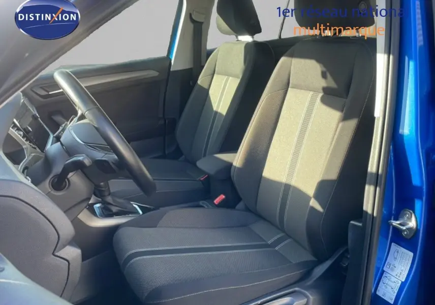 Vue intérieure côté conducteur du Volkswagen T-Roc bleu Ravenna, mettant en valeur les sièges en tissu gris avec surpiqûres.