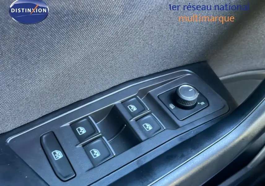 Gros plan sur les commandes des vitres électriques et du réglage des rétroviseurs côté gauche d’un Volkswagen T-Roc bleu Ravenna.