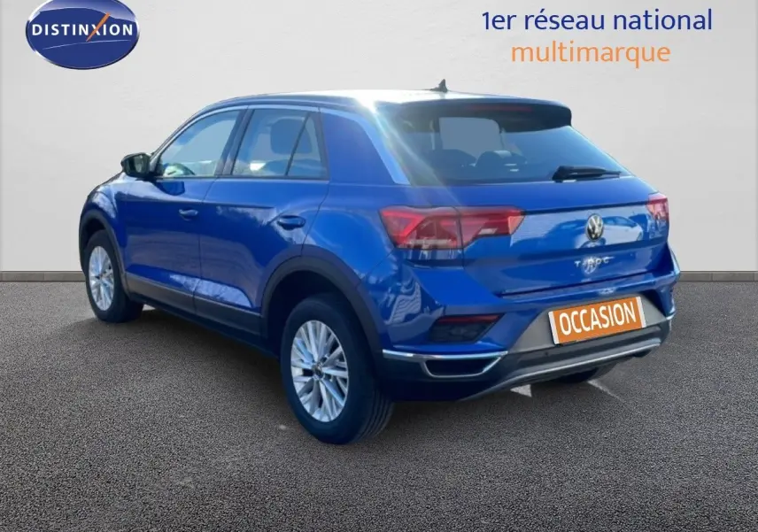 Vue 3/4 arrière droite d'un Volkswagen T-Roc bleu Ravenna métallisé avec jantes alliage et toit noir.