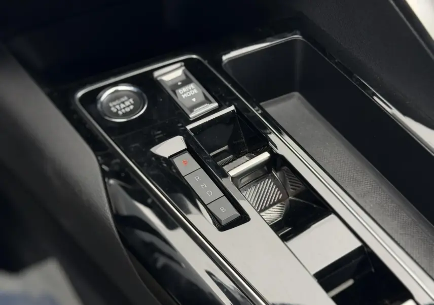 Gros plan sur la console centrale noire brillante du Peugeot 3008 Plug-in Hybrid avec sélecteur de mode et bouton start/stop.