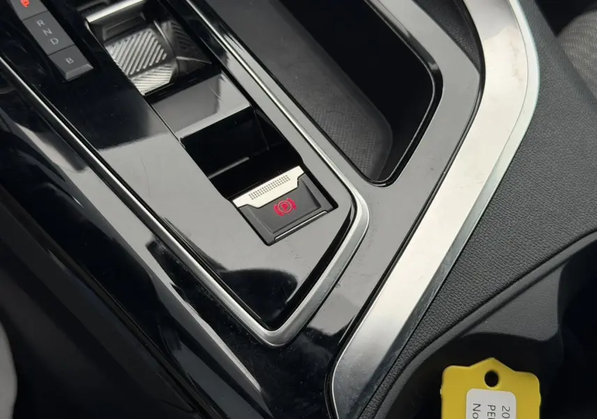 Gros plan sur la console centrale noire du Peugeot 3008 Plug-in Hybrid avec frein de stationnement électrique activé.