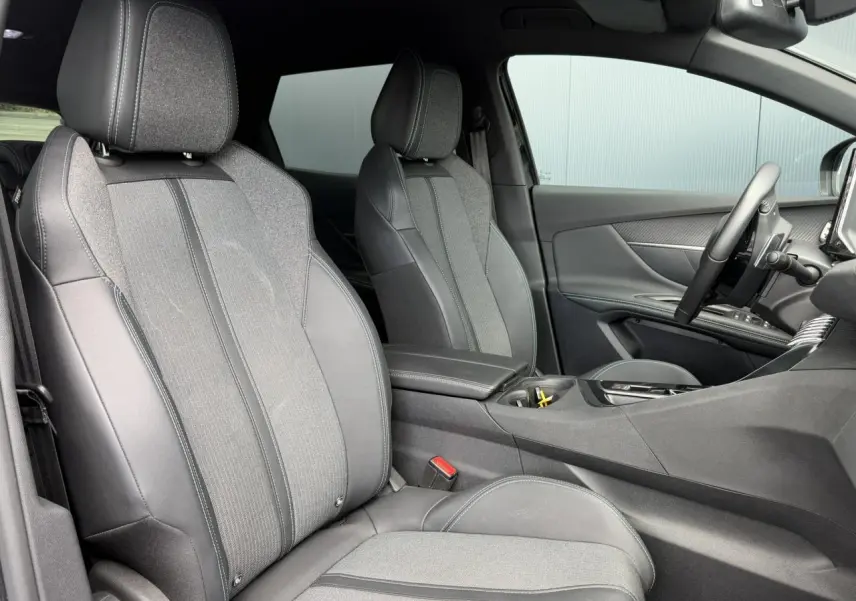 Vue intérieure côté droit du Peugeot 3008 2024, sièges bi-matière gris et noir avec accoudoir central fermé.