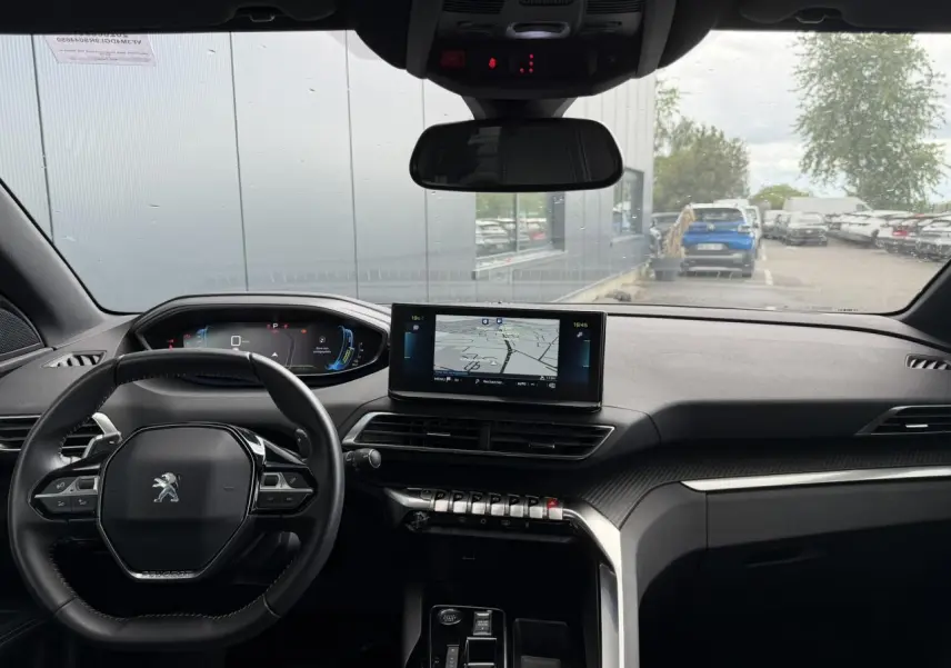 Vue intérieure avant du Peugeot 3008 Plug-in Hybrid 2024, tableau de bord noir avec écran tactile central et volant compact cuir.