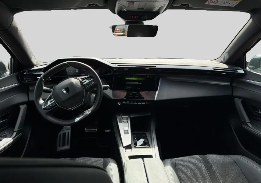 Intérieur noir de la Peugeot 308 1.2 hybrid 145 GT, vue de face sur le tableau de bord et volant multifonction.