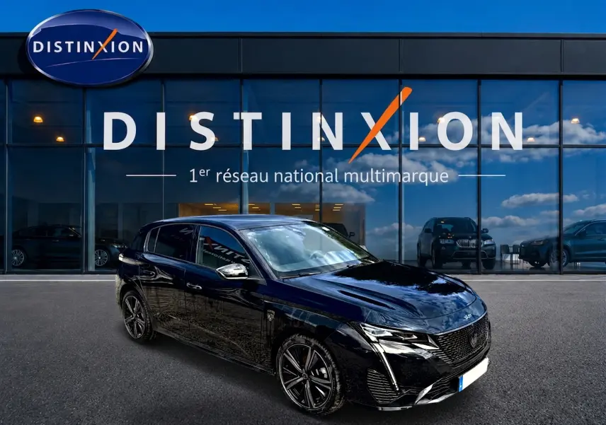 Peugeot 308 1.2 hybrid 145 GT noir vue 3/4 avant, avec jantes alu et calandre distinctive devant un showroom Distinxion.