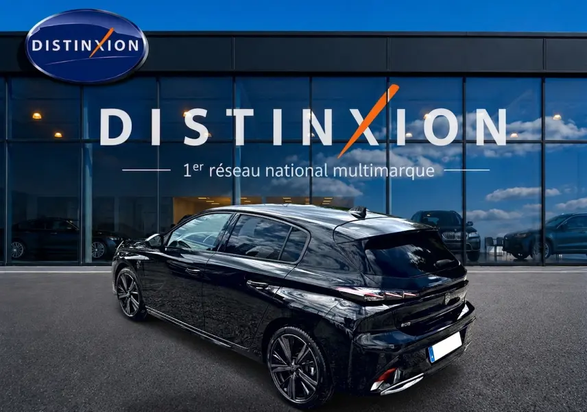 Peugeot 308 1.2 hybrid 145 GT noir vue 3/4 arrière droit, jantes alu et vitres surteintées devant un showroom Distinxion.