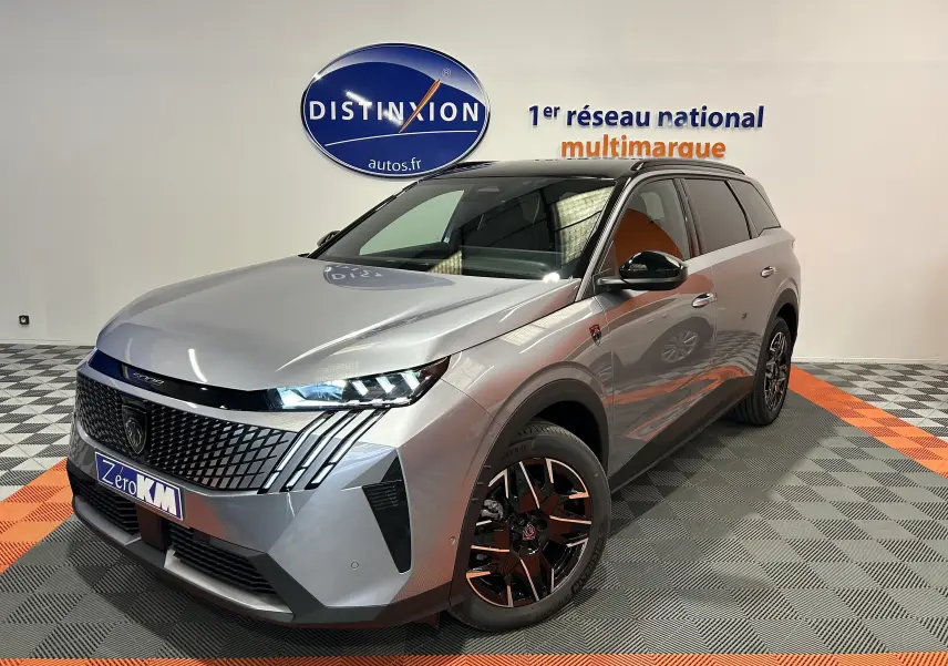 Peugeot 5008 III GT Hybrid gris Artense en 3/4 avant droit, avec jantes bi-ton et calandre distinctive.