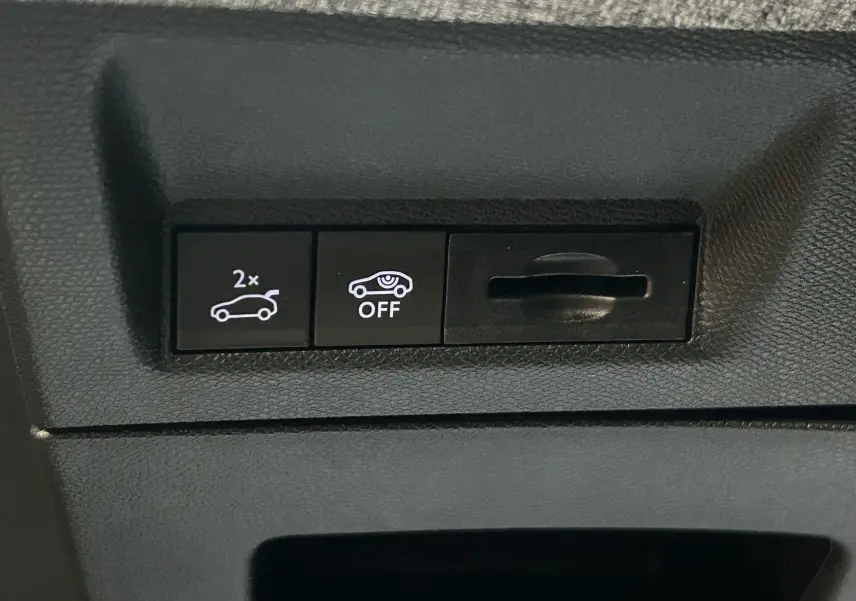Boutons de commande du hayon électrique et du système d'alerte de trafic arrière sur un Peugeot 5008 gris Artense, vue intérieure.
