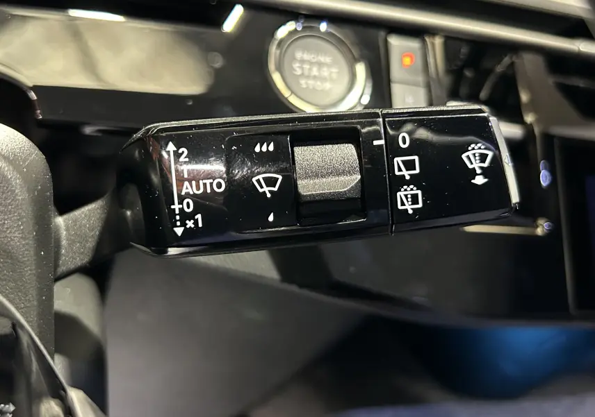 Gros plan sur la commande des essuie-glaces du Peugeot 5008 gris Artense, avec bouton démarrage visible en arrière-plan.