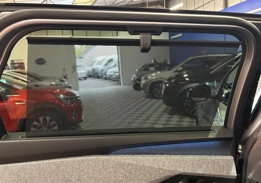 Vue intérieure de la porte arrière droite du Peugeot 5008 gris Artense avec pare-soleil intégré et tissu clair.