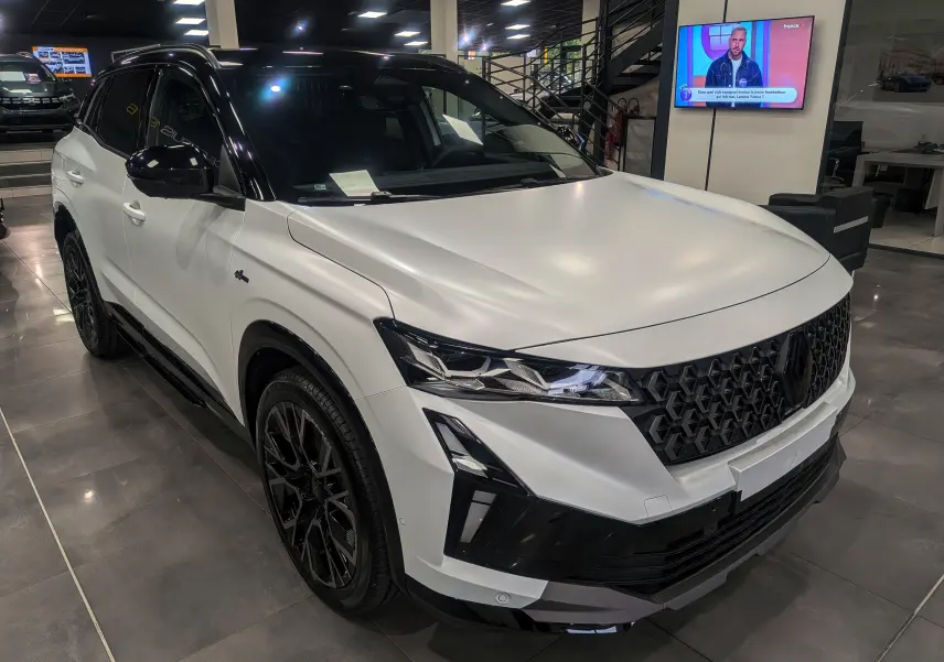 Renault Austral blanc nacré satin avec toit noir, vu en 3/4 avant droit, mettant en valeur sa calandre et ses phares LED.