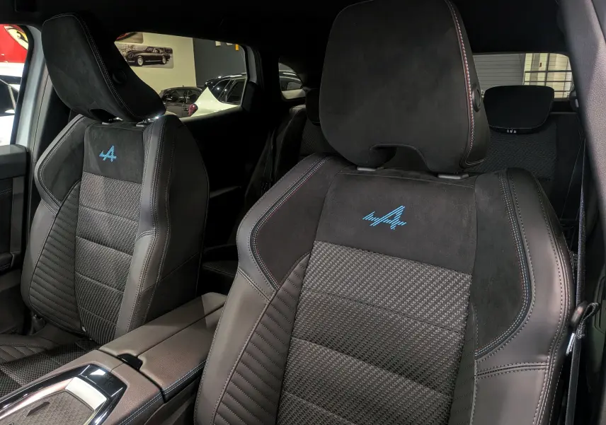 Gros plan sur les sièges avant noirs en cuir et alcantara avec logo Alpine bleu du Renault Austral 2025.