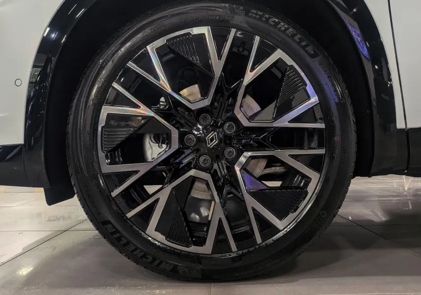 Gros plan sur la jante noire et argentée du Renault Austral blanc nacré satin, soulignant le design moderne et le logo central.