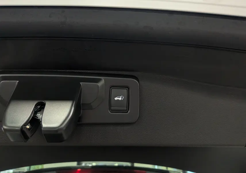 Bouton d'ouverture électrique du hayon sur le coffre intérieur du Renault Austral blanc nacré 2025.