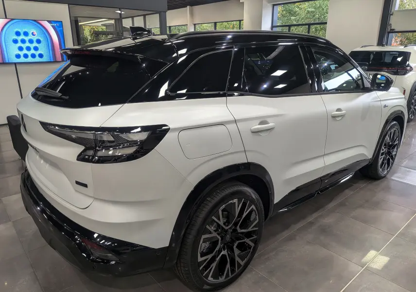 Vue 3/4 arrière droit du Renault Austral blanc nacré satin avec toit noir et jantes noires en concession.