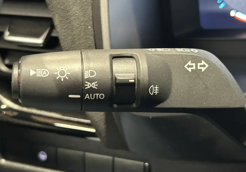 Gros plan sur la commande des feux et clignotants du Nissan Qashqai 2025, intérieur noir.