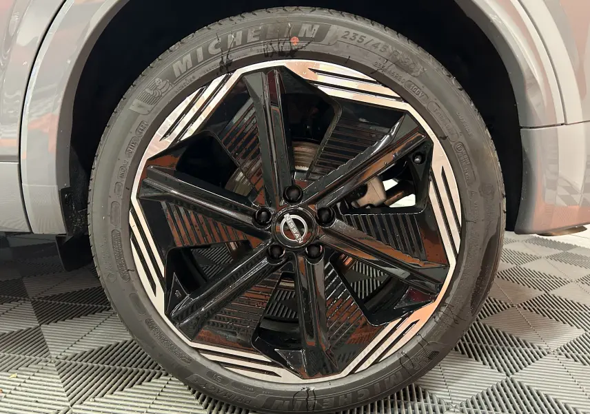 Gros plan sur la roue avant droite du Nissan Qashqai gris céramique avec jante noire et argentée au design moderne.