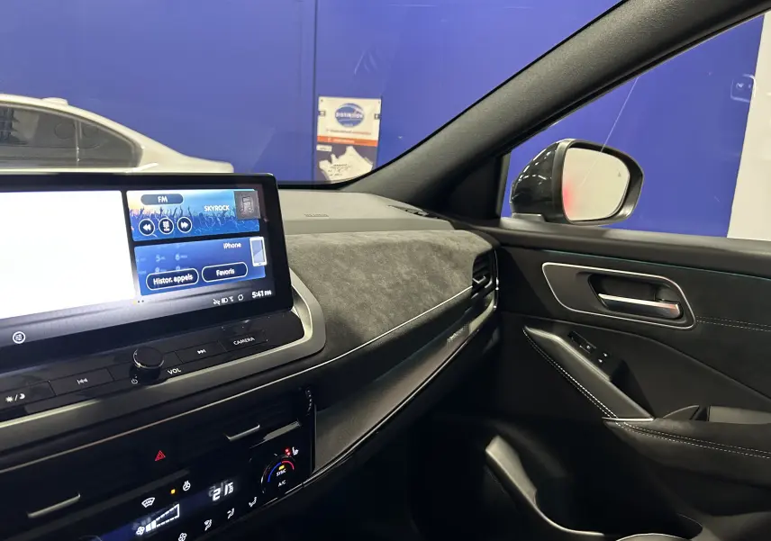 Vue intérieure côté passager du tableau de bord et de la porte du Nissan Qashqai 2025 avec écran tactile et finition noire élégante.
