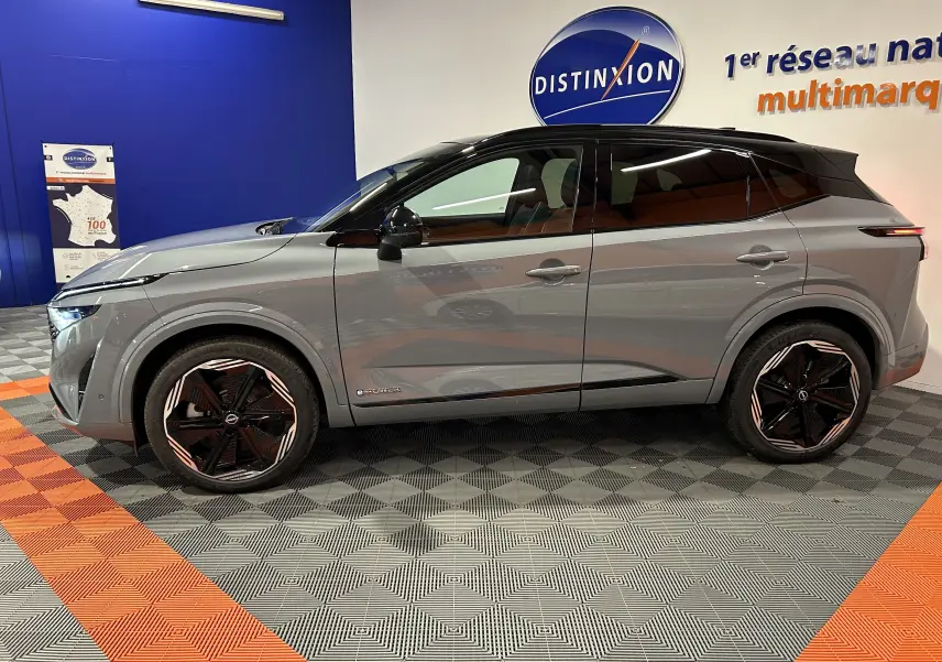 Vue de profil côté gauche du Nissan Qashqai 2025 gris céramique métal avec toit noir panoramique et jantes noires distinctives.