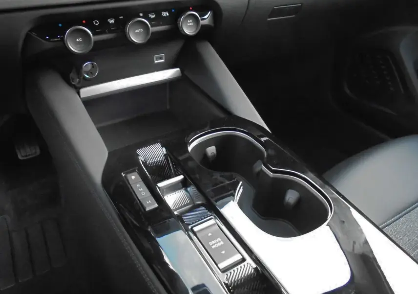 Gros plan sur la console centrale noire brillante du Citroën C5 X 2022 avec commandes de boîte auto et porte-gobelets.