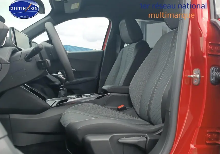 Vue intérieure côté conducteur de la Peugeot 2008 rouge elixir, mettant en valeur les sièges en tissu gris et la console centrale.