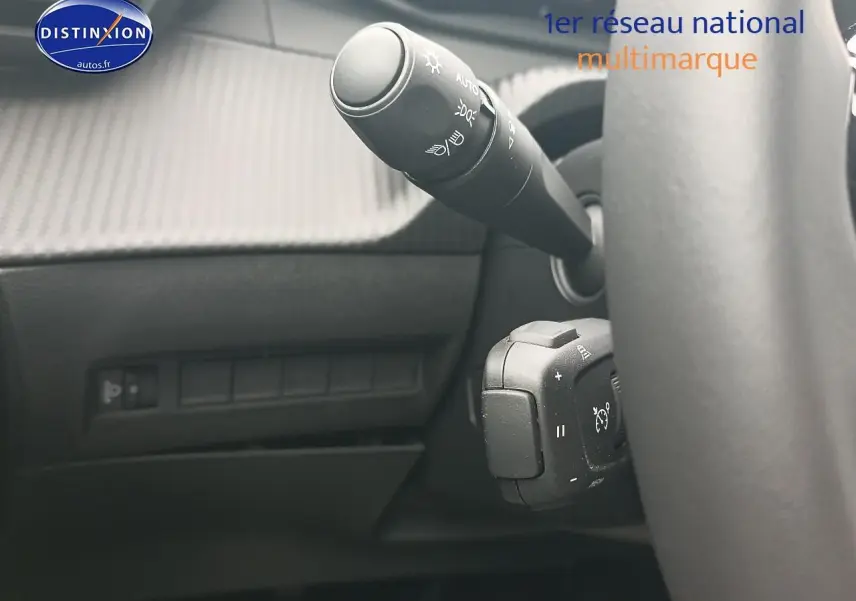 Gros plan sur la commande des phares et régulateur de vitesse derrière le volant d’un Peugeot 2008, intérieur noir.