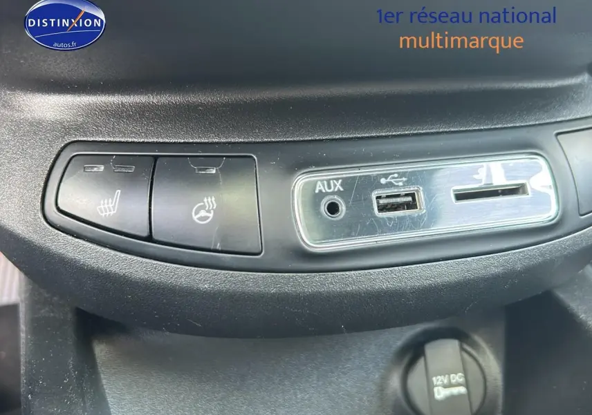 Gros plan sur les commandes de chauffage de siège et les prises AUX, USB et 12V du tableau de bord d'une Fiat 500X rouge.