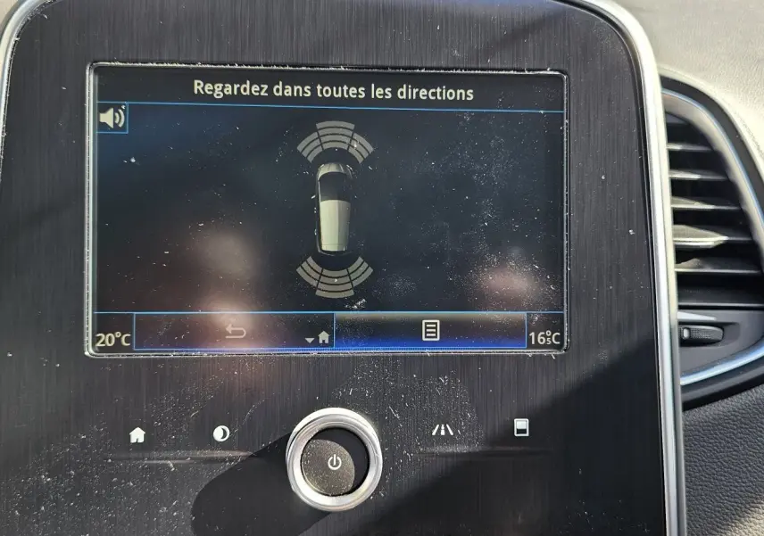 Écran central du tableau de bord d'une Renault Scénic 2020 affichant l'aide au stationnement, entouré d'aérateurs noirs.
