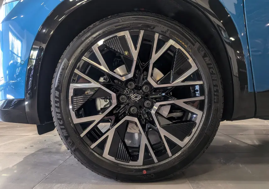 Gros plan sur la roue avant gauche du Renault Austral bleu outremer avec jante alliage noire et argentée au design géométrique.