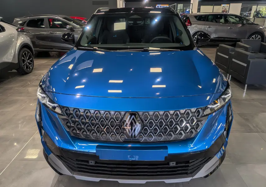 Vue avant d'un Renault Austral bleu outremer avec toit noir, mettant en valeur sa calandre hexagonale distinctive en showroom.