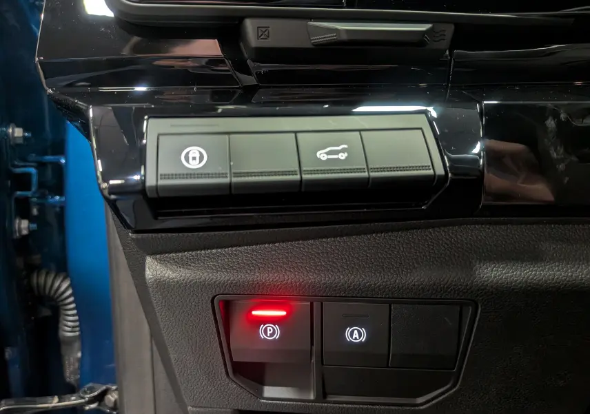 Gros plan sur les commandes intérieures du Renault Austral 2025 bleu outremer, avec bouton de frein à main électronique allumé.