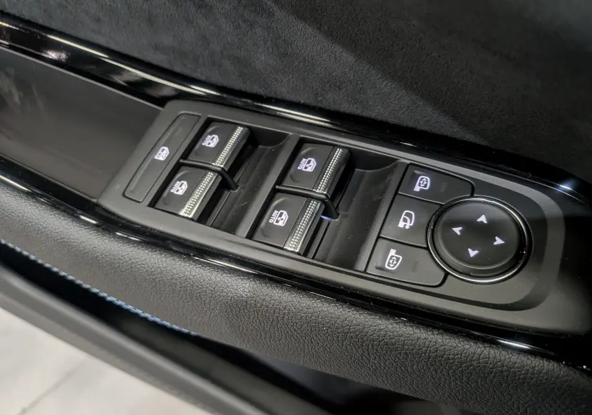 Panneau de commandes des vitres et rétroviseurs sur la porte côté gauche d’un Renault Austral bleu Outremer 2025.