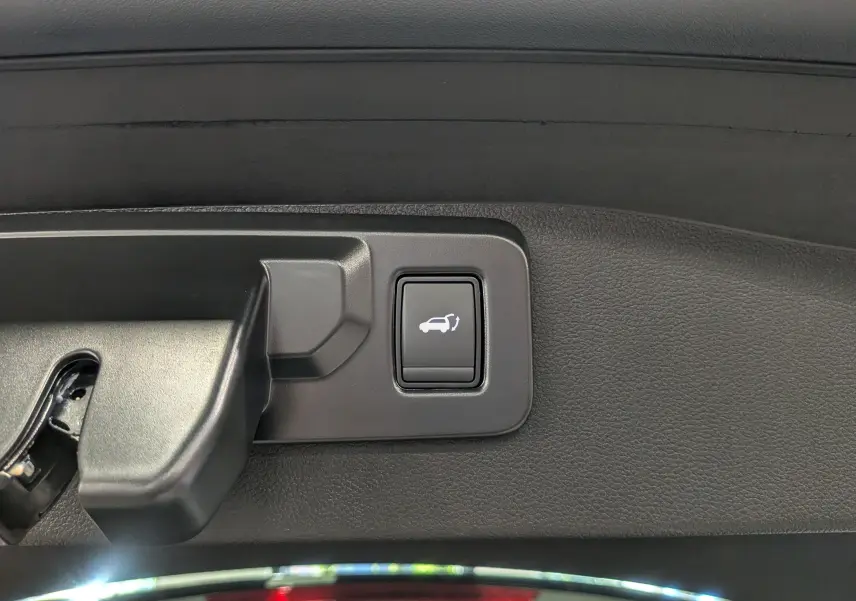 Bouton d'ouverture électrique du coffre sur la garniture intérieure d'une Renault Austral 2025 bleu outremer toit noir.