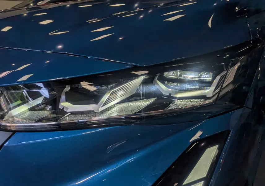 Gros plan sur le phare avant droit du Renault Austral bleu Outremer, soulignant les détails lumineux modernes.