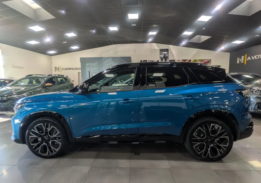 Profil côté gauche du Renault Austral 2025 bleu outremer avec toit noir et jantes alliage distinctives en showroom.