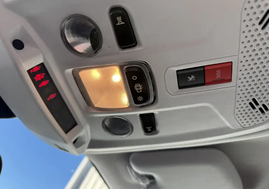 Plafonnier intérieur allumé avec boutons SOS et éclairage, dans un Peugeot 2008 gris diesel 2020, vue vers le toit