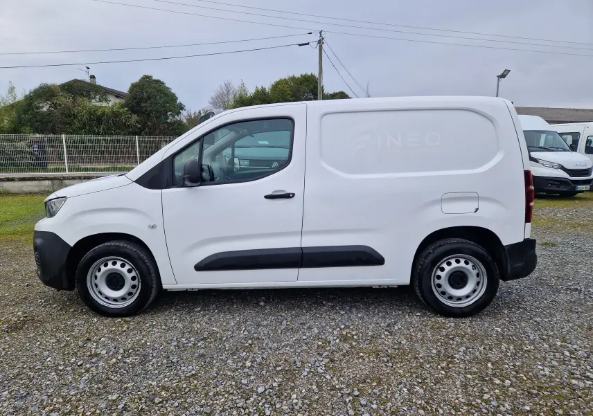 Vue de profil côté gauche d'un utilitaire Peugeot Partner blanc de 2020 avec protections noires sur les portières.